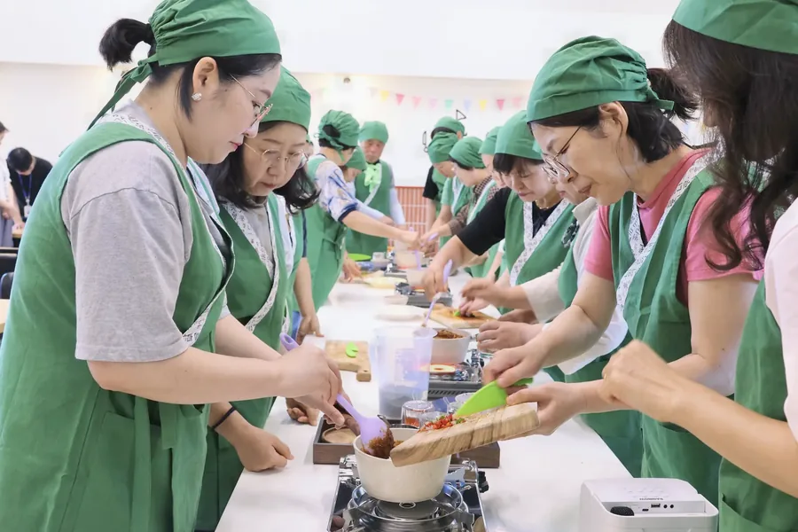 순창 장류 체험 안내: 초록 두건과 앞치마를 입고 함께 재료를 섞는 참가자들
